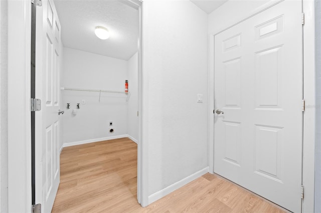 washroom featuring hookup for an electric dryer, light wood-type flooring, a textured ceiling, and hookup for a washing machine