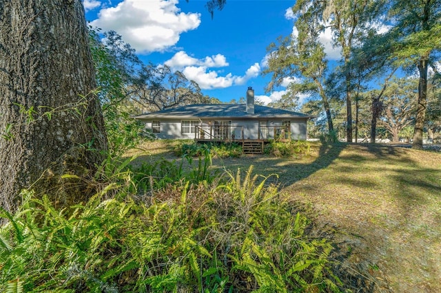 rear view of house featuring a lawn and a wooden deck