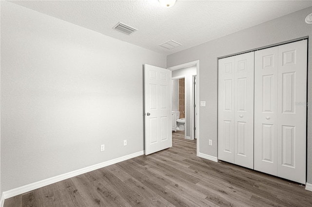 unfurnished bedroom with hardwood / wood-style floors, a textured ceiling, and a closet