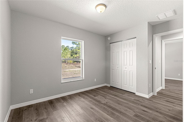 unfurnished bedroom with dark hardwood / wood-style flooring, a closet, and a textured ceiling