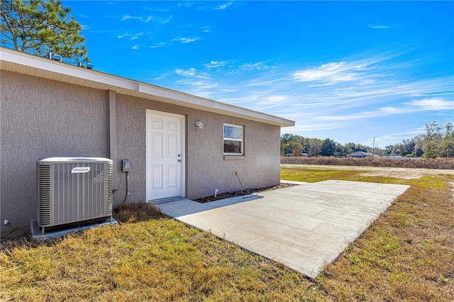 entrance to property featuring a yard, a patio, and central AC