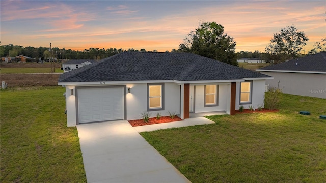 ranch-style home with an attached garage, a shingled roof, concrete driveway, and a front yard