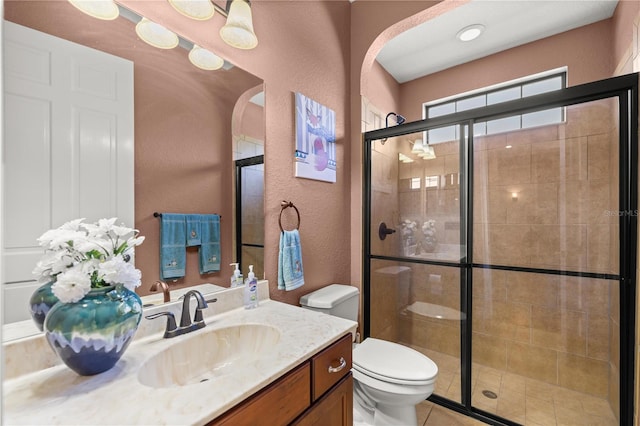 bathroom featuring tile patterned flooring, vanity, a shower with door, and toilet