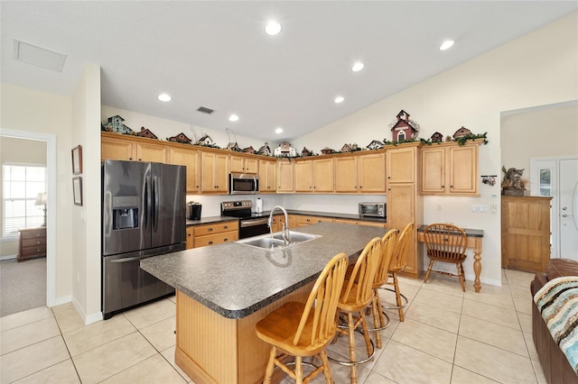 kitchen with light tile patterned flooring, sink, stainless steel appliances, and an island with sink