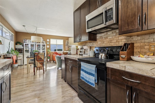 kitchen featuring black range with electric stovetop, dark brown cabinets, and pendant lighting