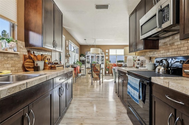 kitchen featuring dark brown cabinetry, pendant lighting, plenty of natural light, and appliances with stainless steel finishes