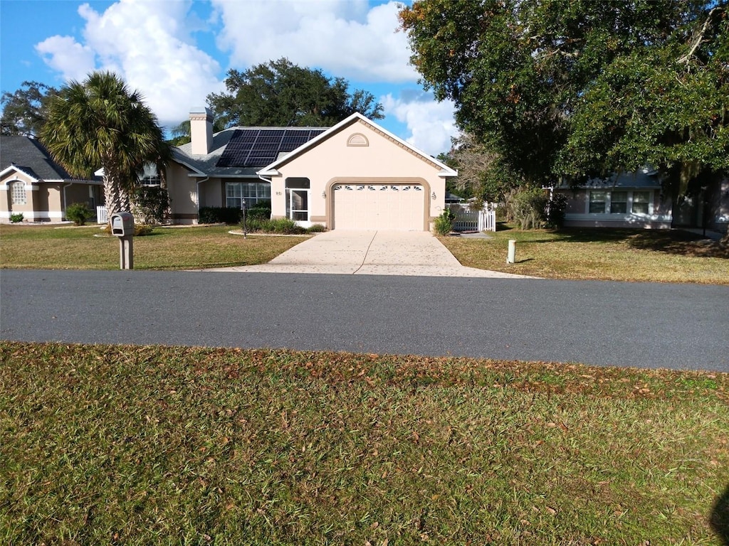 view of front of home with a garage, a front yard, and solar panels