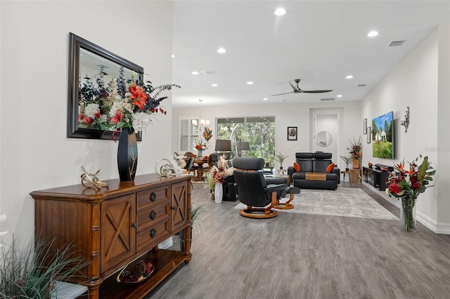 living room featuring wood-type flooring and ceiling fan with notable chandelier