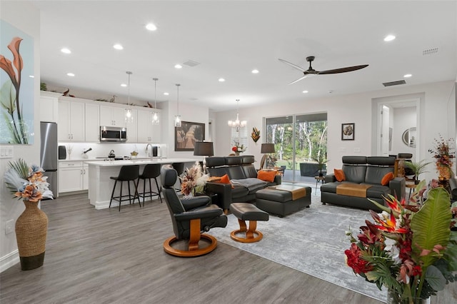 living room featuring hardwood / wood-style floors, ceiling fan with notable chandelier, and sink