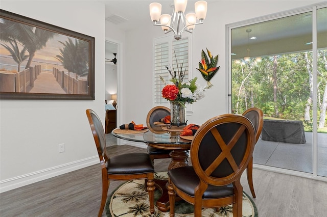 dining space with ceiling fan with notable chandelier and wood-type flooring