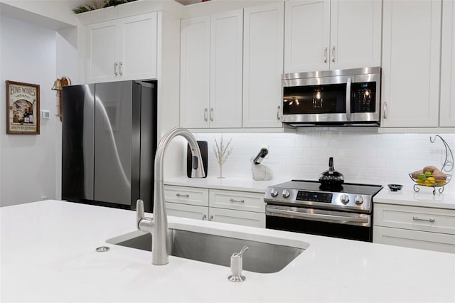 kitchen featuring tasteful backsplash, white cabinetry, sink, and appliances with stainless steel finishes