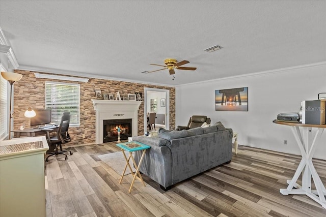 living room with hardwood / wood-style floors, a textured ceiling, ceiling fan, and crown molding