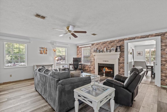 living room with a textured ceiling, light hardwood / wood-style floors, ceiling fan, and crown molding