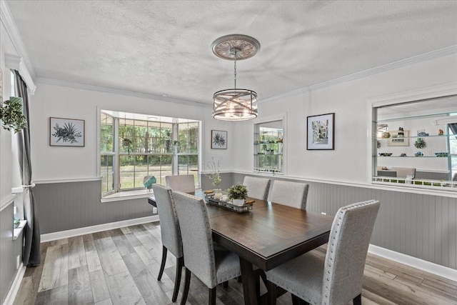 dining area with a textured ceiling, a chandelier, crown molding, and light hardwood / wood-style flooring