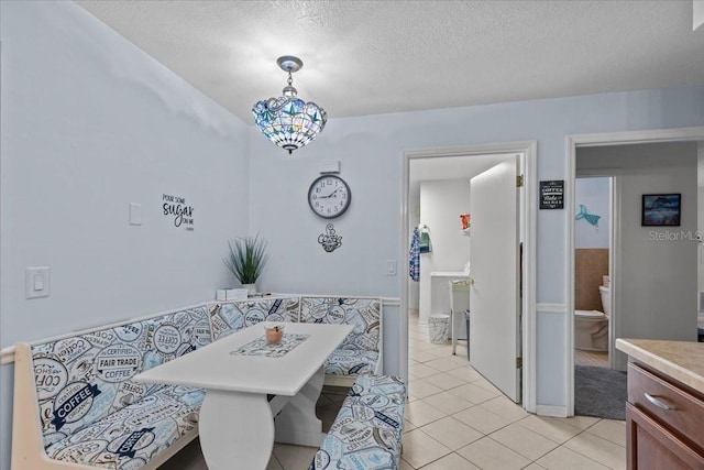 tiled dining room featuring a chandelier and a textured ceiling