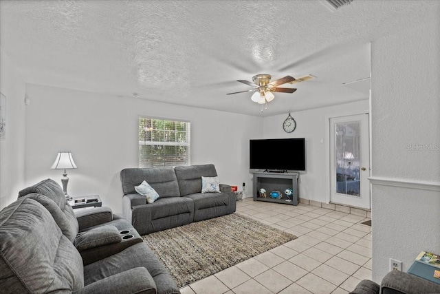 living room with ceiling fan, light tile patterned floors, and a textured ceiling