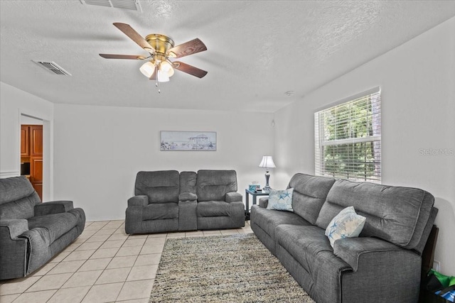 living room featuring ceiling fan, light tile patterned floors, and a textured ceiling