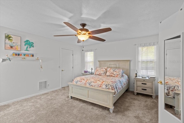 carpeted bedroom with multiple windows, a textured ceiling, and ceiling fan