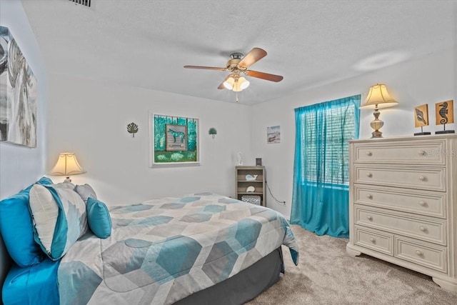 carpeted bedroom with ceiling fan and a textured ceiling