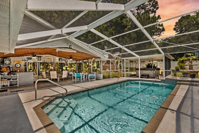 pool at dusk with glass enclosure and a patio