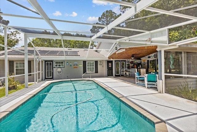 view of pool with a patio, glass enclosure, and ceiling fan