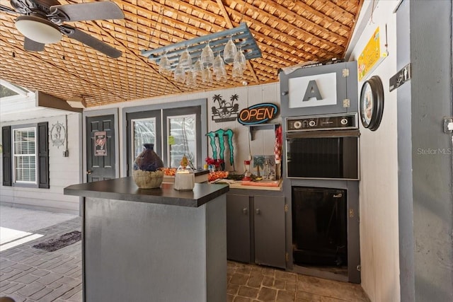 kitchen featuring brick ceiling, black oven, ceiling fan, and vaulted ceiling