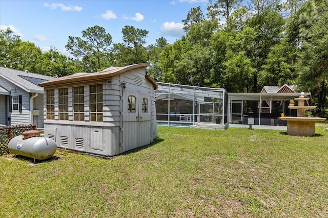 rear view of house featuring a pool, a lanai, and a lawn