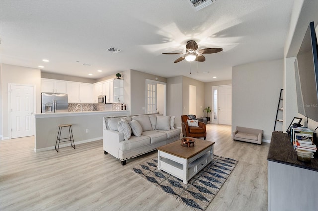 living room featuring a textured ceiling, light hardwood / wood-style floors, and ceiling fan