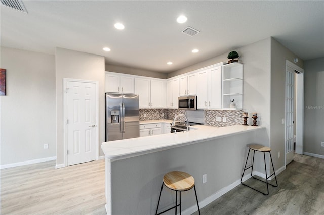 kitchen featuring white cabinetry, kitchen peninsula, stainless steel appliances, and a breakfast bar area