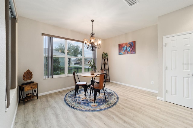 dining area with light wood-type flooring and a notable chandelier