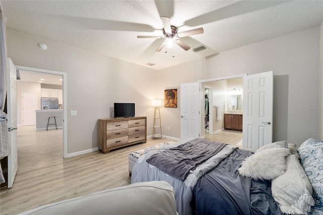 bedroom with stainless steel refrigerator with ice dispenser, a textured ceiling, light hardwood / wood-style flooring, and ceiling fan