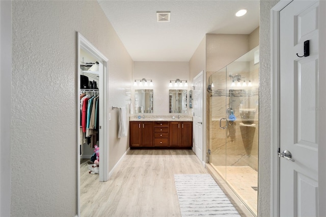 bathroom featuring vanity, wood-type flooring, a textured ceiling, and walk in shower