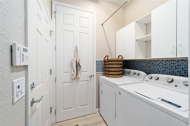 washroom featuring washing machine and dryer, light hardwood / wood-style flooring, and cabinets