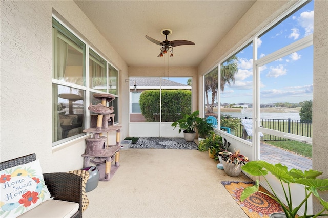 sunroom with ceiling fan and a water view