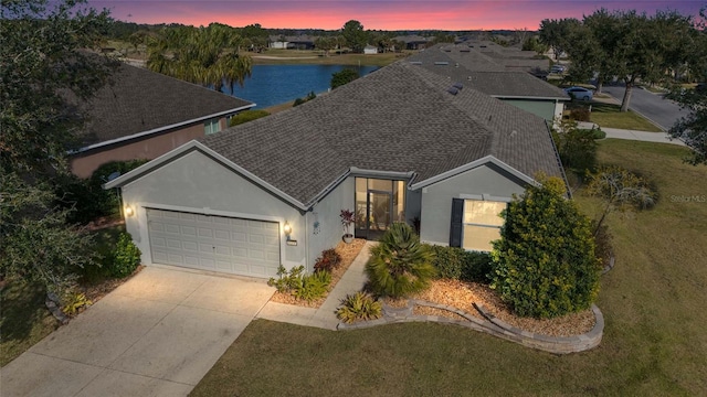 view of front of house featuring a water view, a garage, and a lawn