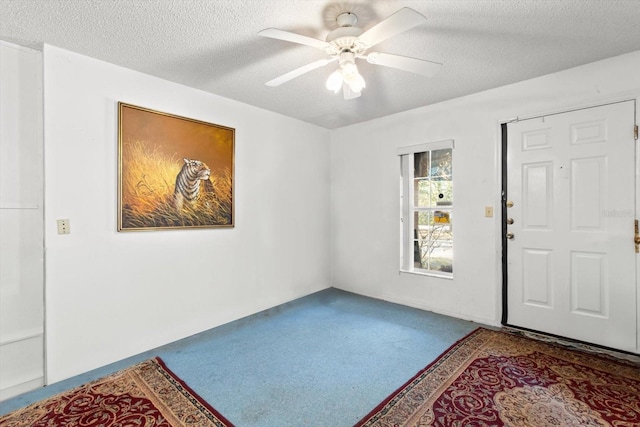 carpeted entrance foyer with a textured ceiling and ceiling fan