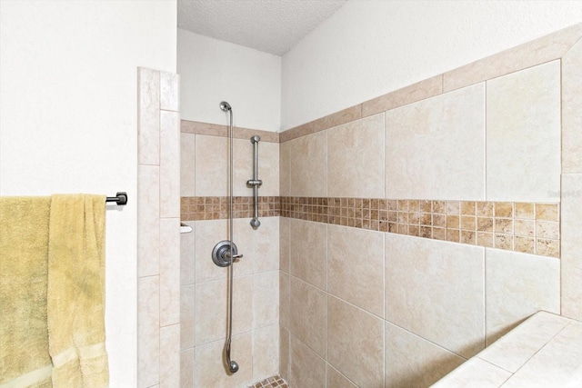 bathroom with a tile shower and a textured ceiling