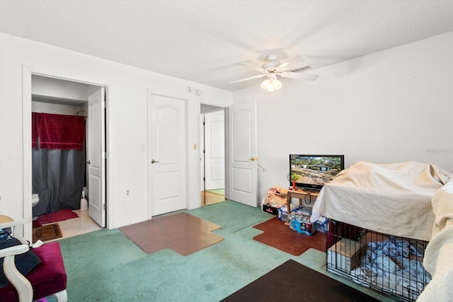 carpeted bedroom featuring a textured ceiling, ceiling fan, and ensuite bathroom