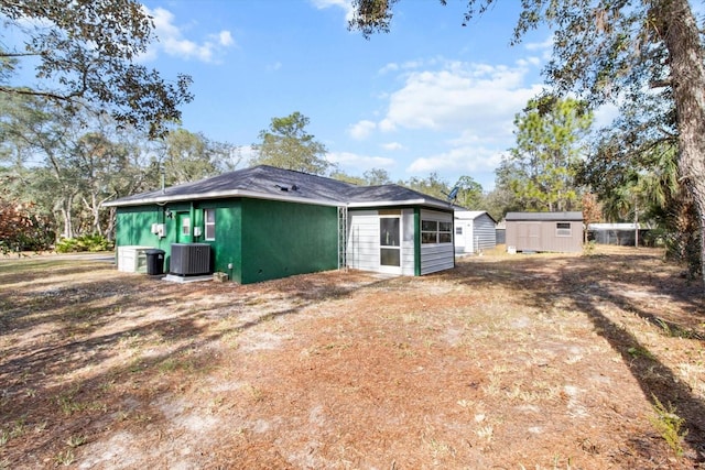 rear view of property with central AC and a storage shed