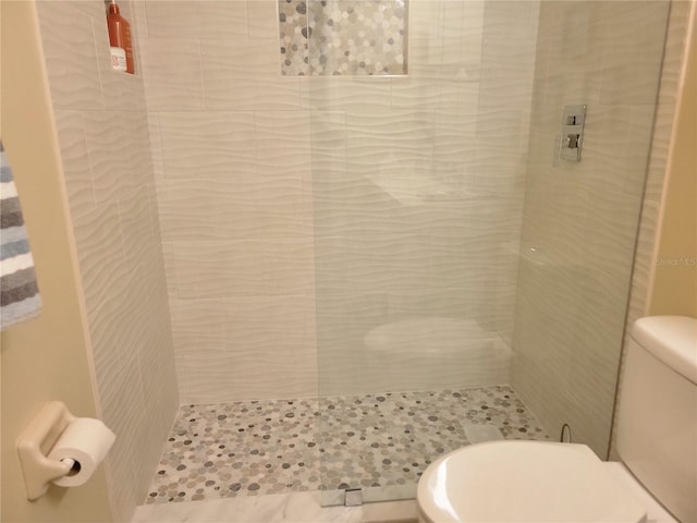 bathroom featuring toilet and a tile shower