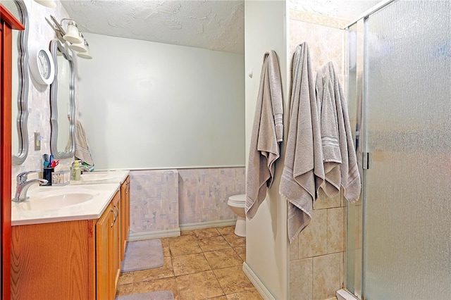 bathroom with toilet, vanity, a textured ceiling, and walk in shower