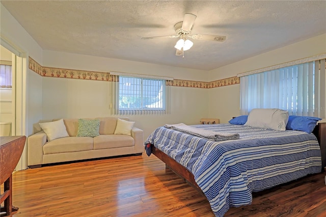 bedroom featuring wood-type flooring, a textured ceiling, and ceiling fan