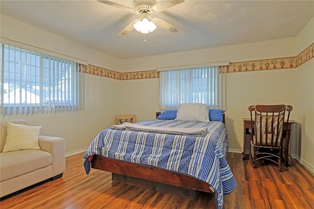 bedroom featuring multiple windows, dark hardwood / wood-style flooring, and ceiling fan