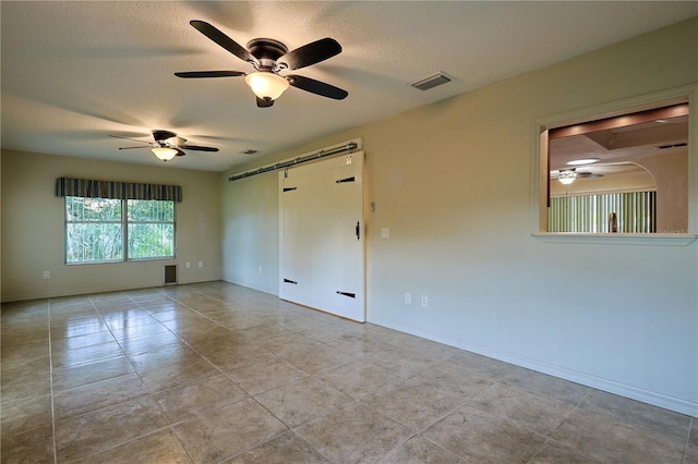 10185 SE 175th Ln, Summerfield, FL 34491 - unfurnished room featuring a ceiling fan, a barn door, a textured ceiling, baseboards, and tile patterned flooring