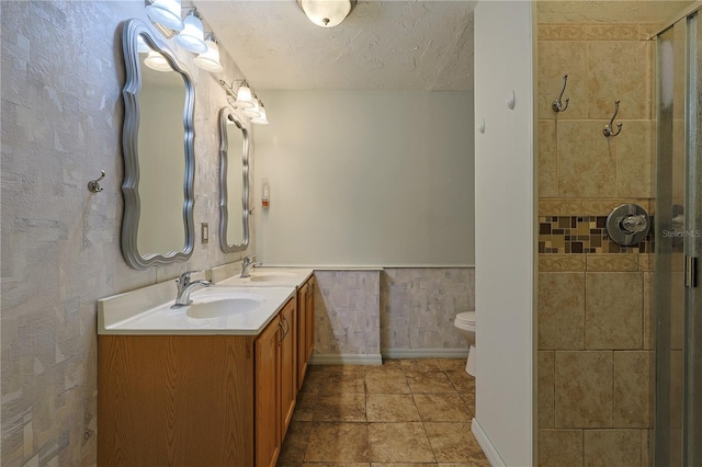 10185 SE 175th Ln, Summerfield, FL 34491 - bathroom with double vanity, tiled shower, toilet, a textured ceiling, and a wainscoted wall