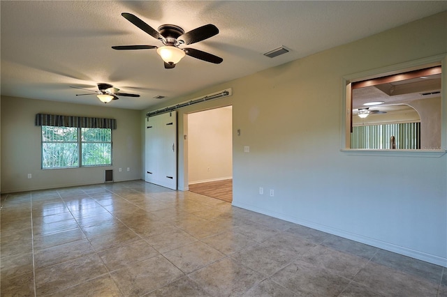 10185 SE 175th Ln, Summerfield, FL 34491 - unfurnished room with a ceiling fan, a textured ceiling, baseboards, a barn door, and tile patterned flooring