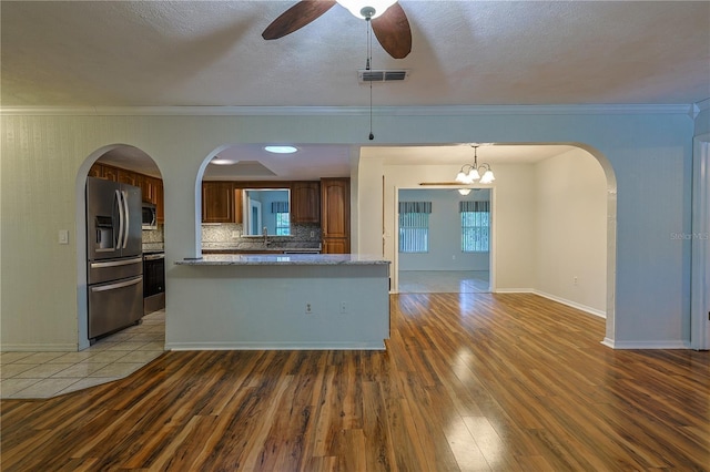 10185 SE 175th Ln, Summerfield, FL 34491 - kitchen with appliances with stainless steel finishes, wood finished floors, a ceiling fan, tasteful backsplash, and ornamental molding