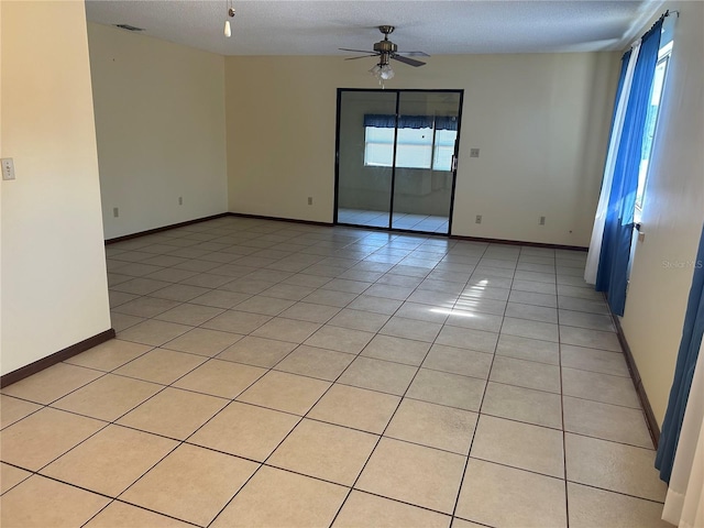 spare room with ceiling fan, a textured ceiling, and light tile patterned floors