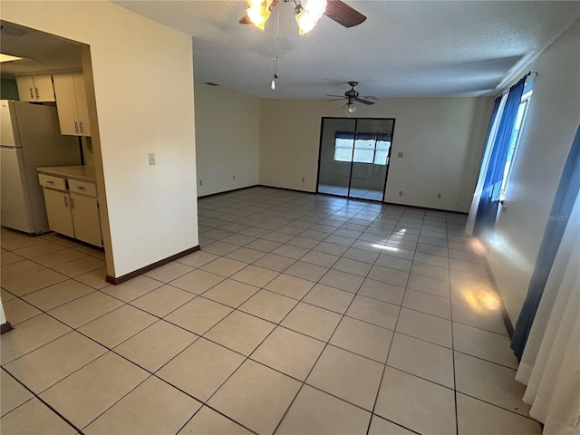 tiled spare room with a textured ceiling and ceiling fan