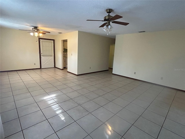 spare room featuring a textured ceiling, ceiling fan, and light tile patterned floors